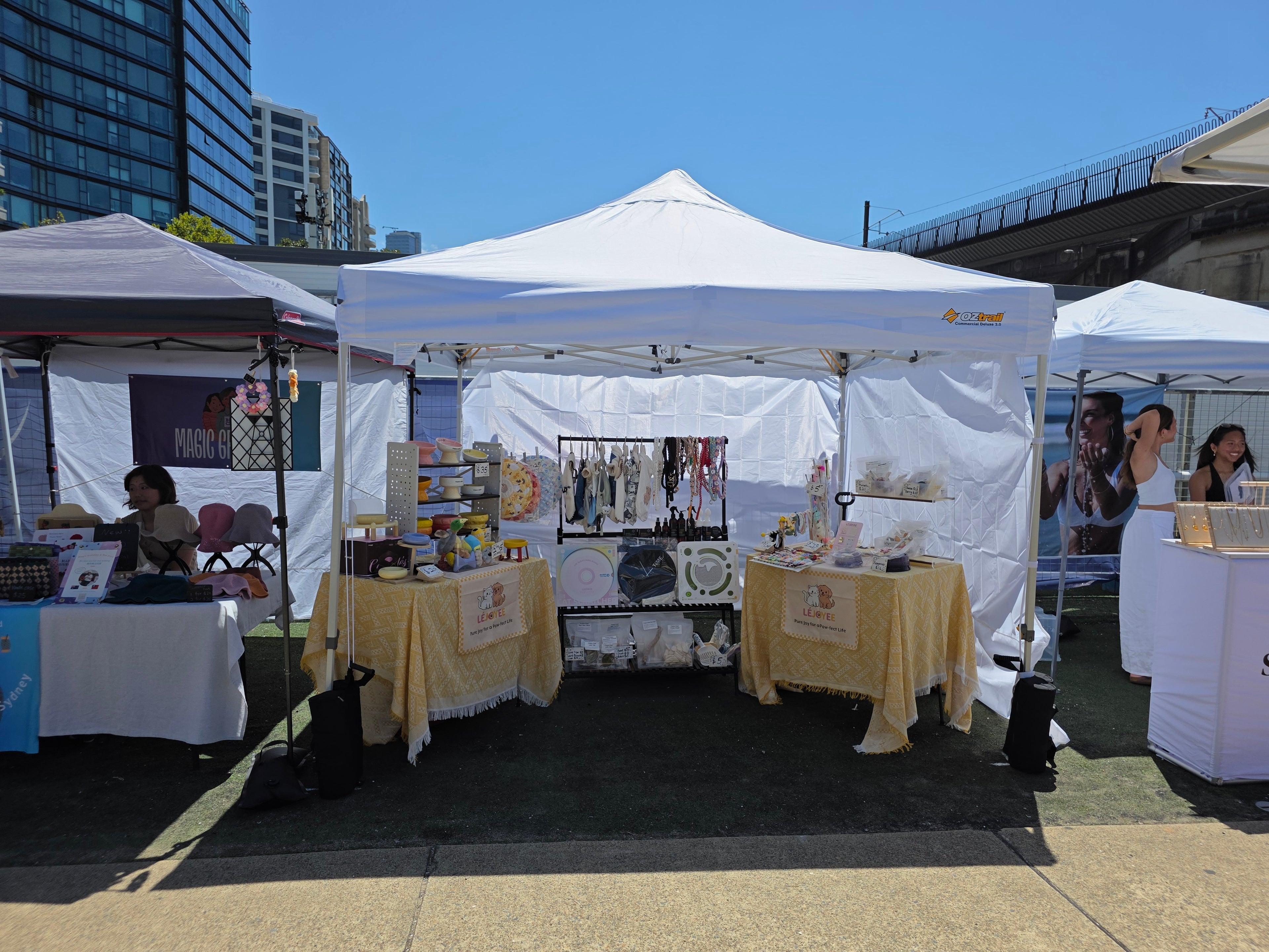 Outdoor market with white tents and tables displaying various pets items.