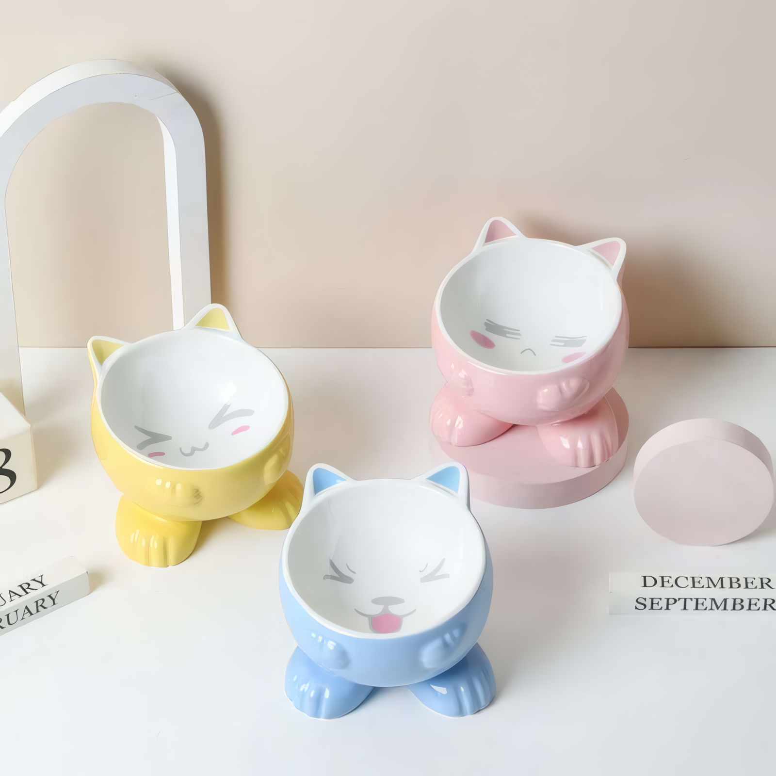 Three colorful cat-shaped bowls on a light surface with a neutral background.