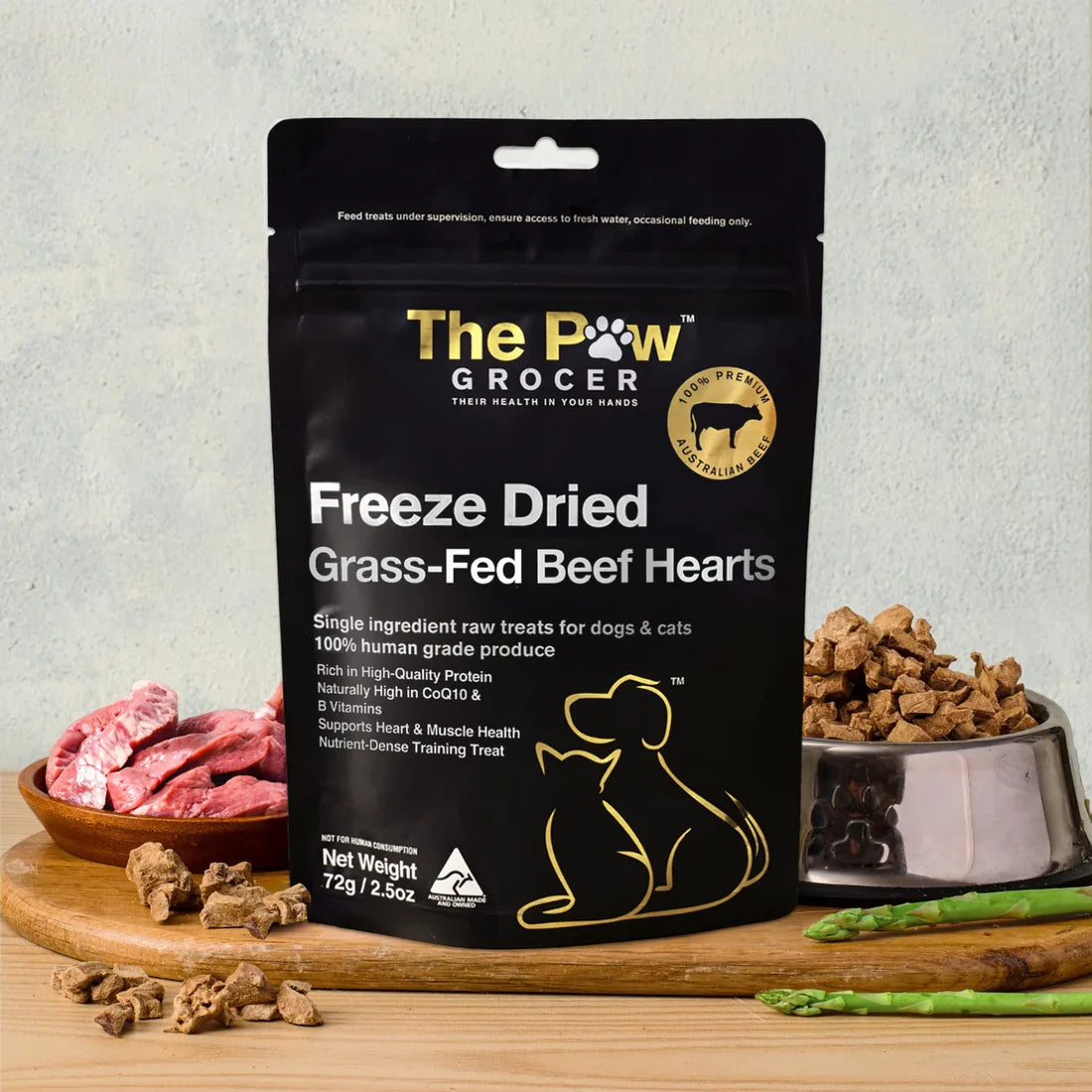 The Paw Grocer 72g Freeze-Dried Beef Hearts treats beautifully displayed on a wooden board next to fresh raw meat and a silver bowl filled with the CoQ10-rich, cardiovascular health-boosting reward.