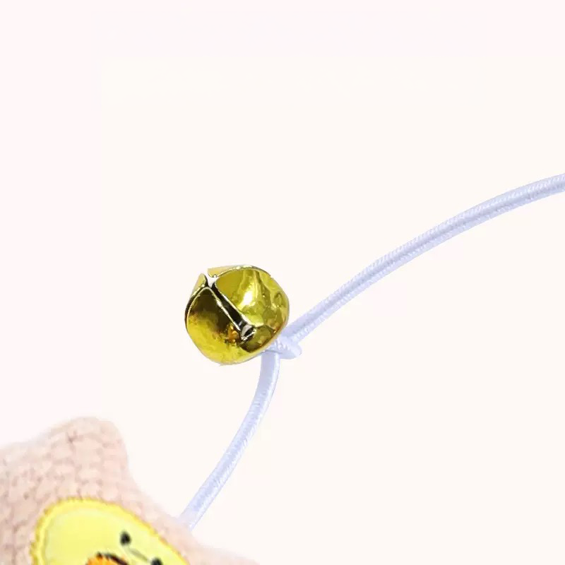 Close-up detail of a crisp golden bell attached to the white bouncy elastic string of a cat teaser wand, designed to instantly grab your Chief Feline Officer&