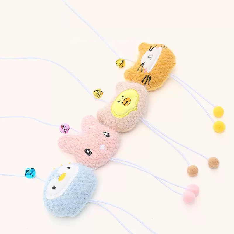 Close-up of four pastel plush cat toys attached to elastic strings, featuring an orange cat, beige chick, pink bunny, and blue penguin, each showcasing safe embroidered faces, golden bells, and dangling pom-pom legs.