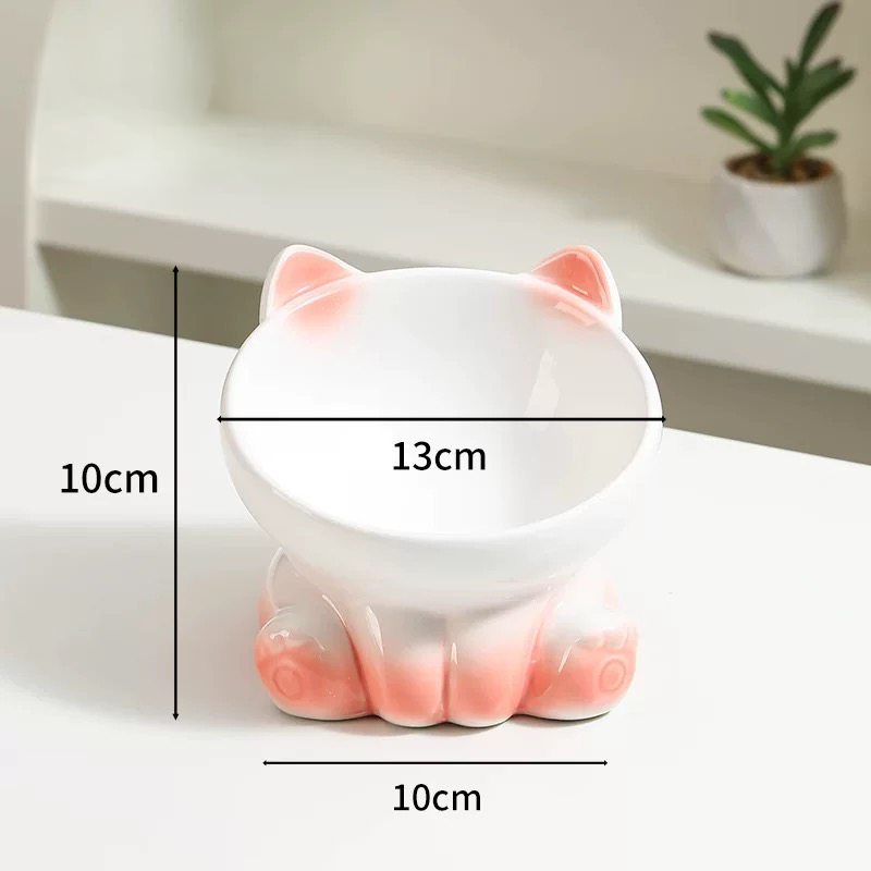 A pink elevated ceramic cat bowl with dimension graphics indicating a 13cm bowl width and a 10cm tall sturdy base.