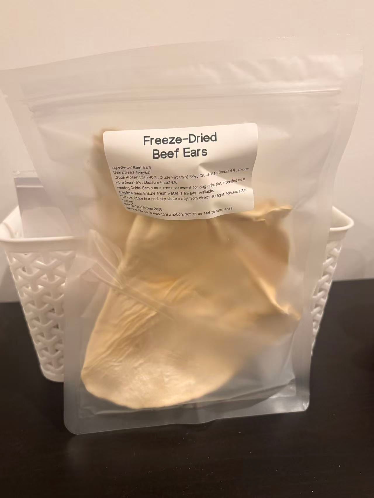 A real-world photo of the Freeze-Dried Beef Ears packaging, featuring a clear label with guaranteed analysis, feeding instructions, and highlighting its 100% natural, single-ingredient purity.