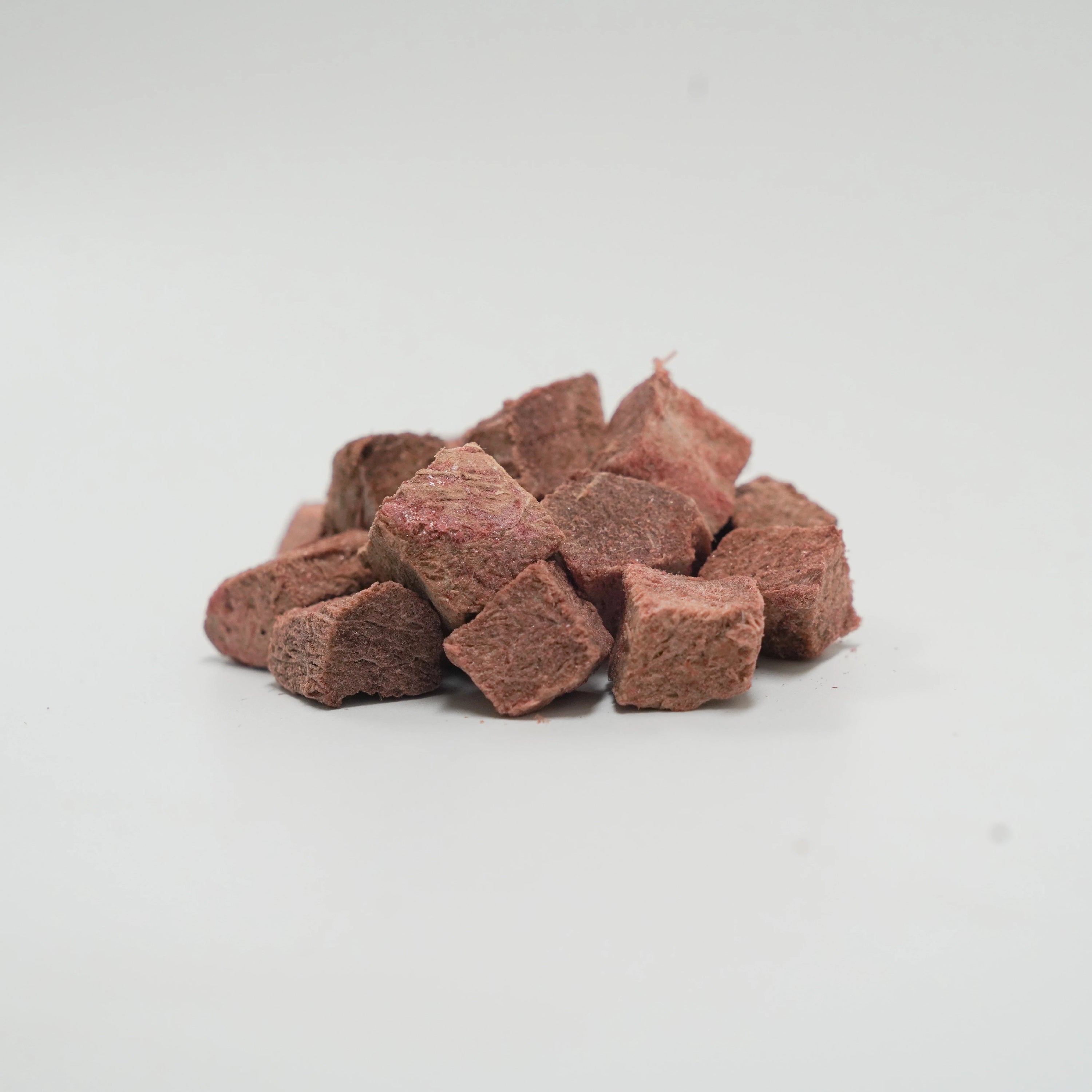 A close-up pile of Rafa Raw freeze-dried emu steak cubes. Dark, chewy, single-ingredient raw red meat treats perfect for picky eaters and pets with food allergies.