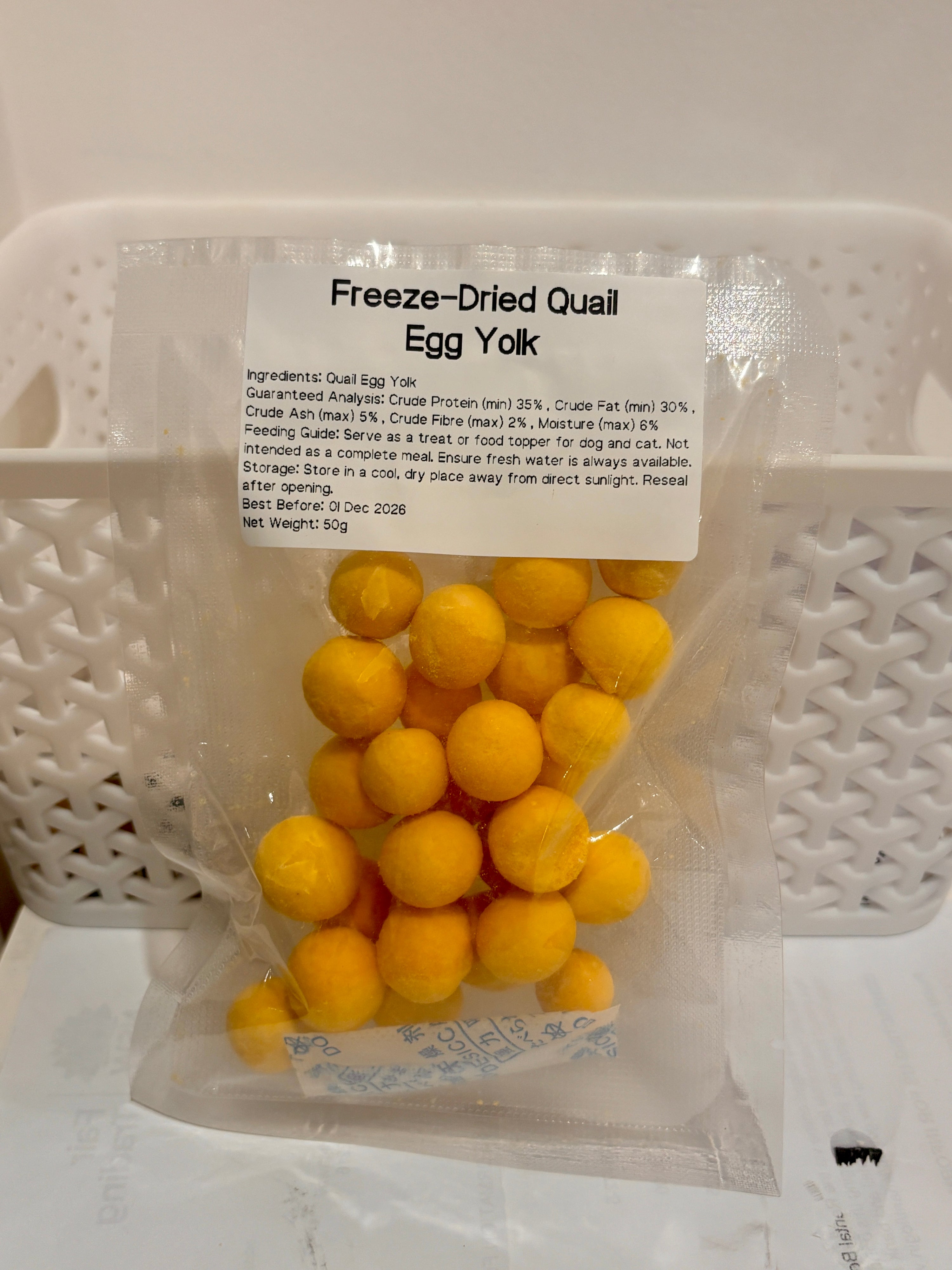 A clear, resealable 50g bag of Freeze-Dried Quail Egg Yolk pet treats, featuring a printed label that details the 100% single-ingredient formula, feeding guide, and guaranteed analysis with a minimum of 35% crude protein.