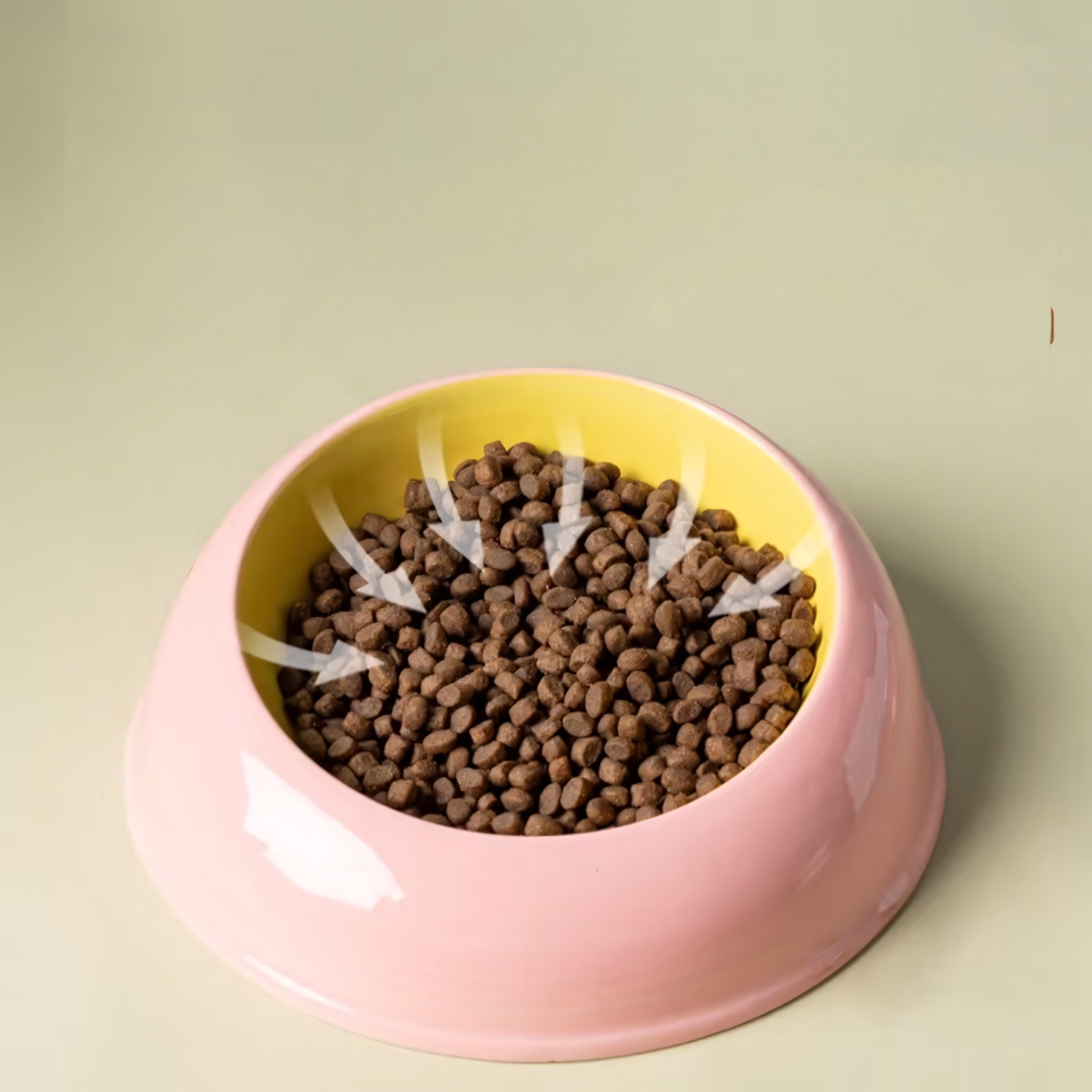 Graphic showing arrows pointing towards the center of the pink and yellow ceramic cat bowl, demonstrating how the curved design naturally gathers kibble to prevent edge-spills.