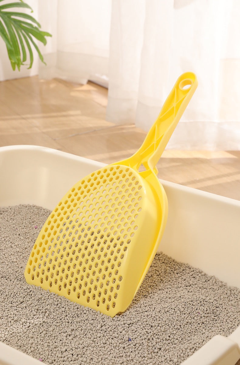 The sturdy yellow round-hole cat litter scoop digging deep into a box of pellet litter, demonstrating its heavy-duty PP material and 14.5cm wide scoop head.