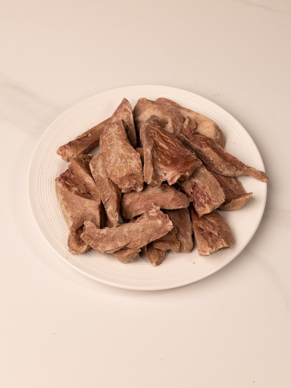 Multiple Beef Heart dog treats in a white plate, grain-free and rich in iron and B-vitamins for active and senior dogs.