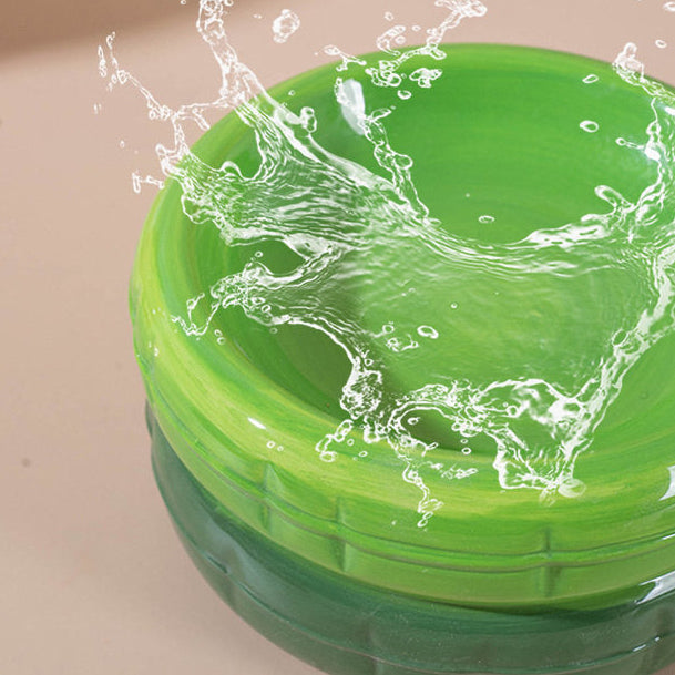 A close-up of water splashing into a vibrant green ceramic cat bowl, demonstrating its smooth, waterproof glossy glaze and hygienic design.
