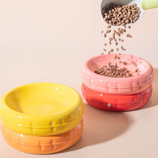 Dry kibble being poured from a scoop into a vibrant pink ceramic cat bowl, showcasing the bowl&