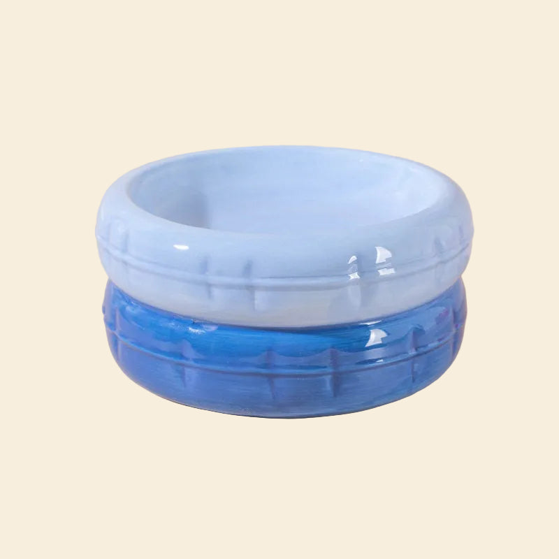 A vibrant two-tone blue ceramic cat bowl featuring a pale blue top and a deep ocean blue base, designed with a glossy glaze and durable ceramic material.