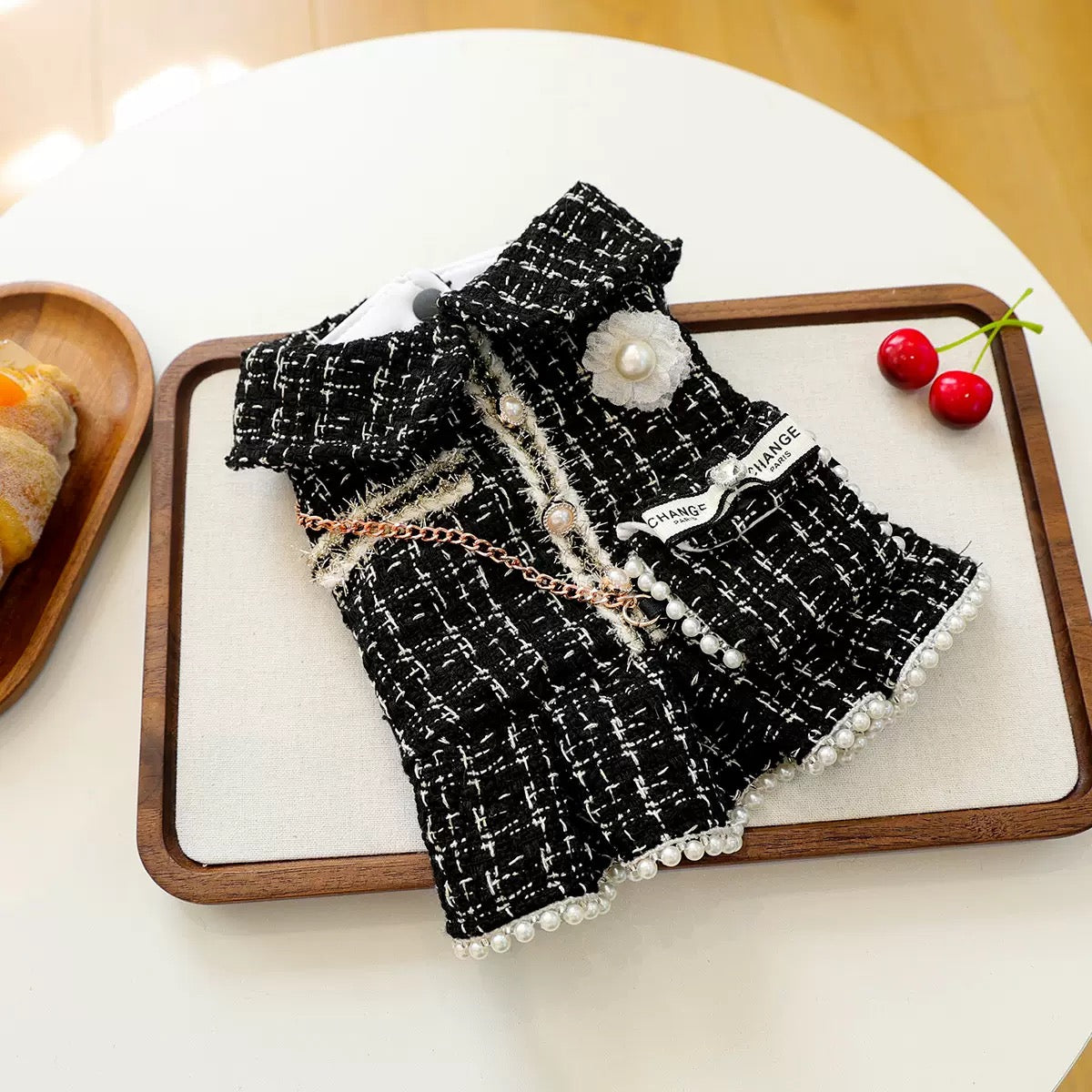 tyled flat lay of the Luxury Tweed Dog Dress with a cherry. Detailed view of the woven tweed texture and &