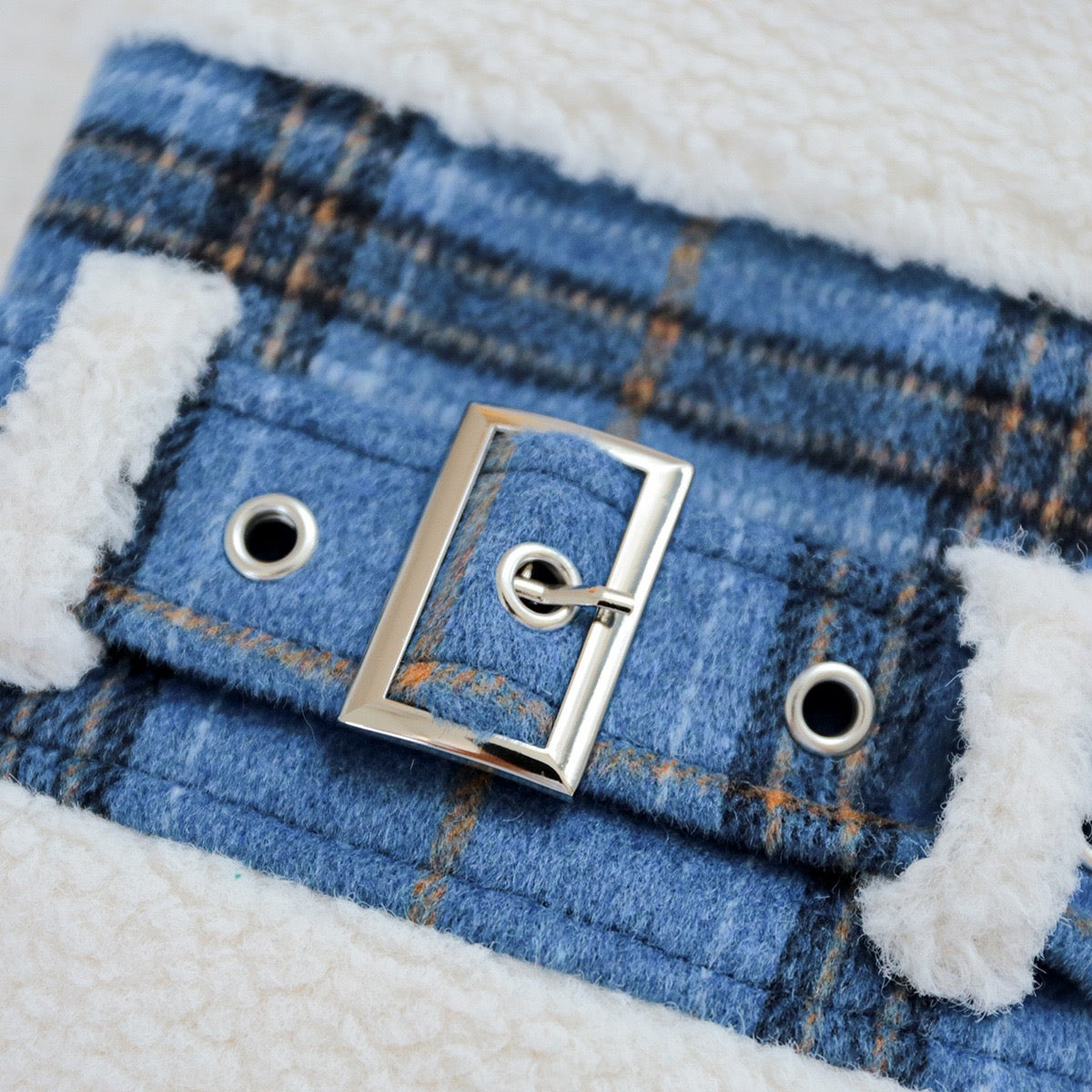 Close-up of the classic silver buckle belt on the blue plaid fabric. Adds a preppy, old-money aesthetic to the winter dog coat
