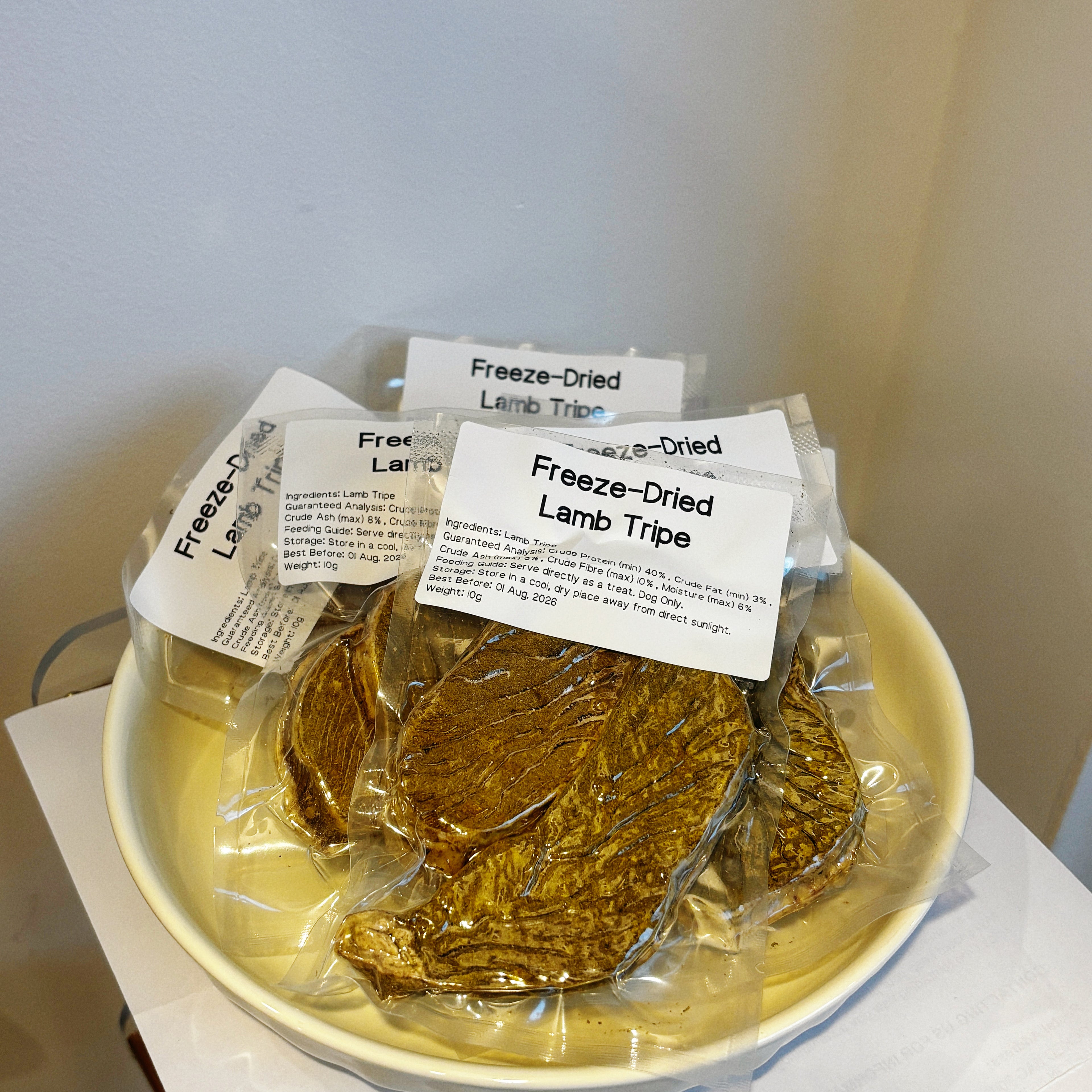 Multiple pouches of Freeze-Dried Lamb Tripe on a plate, a natural probiotic supplement to soothe sensitive dog stomachs.