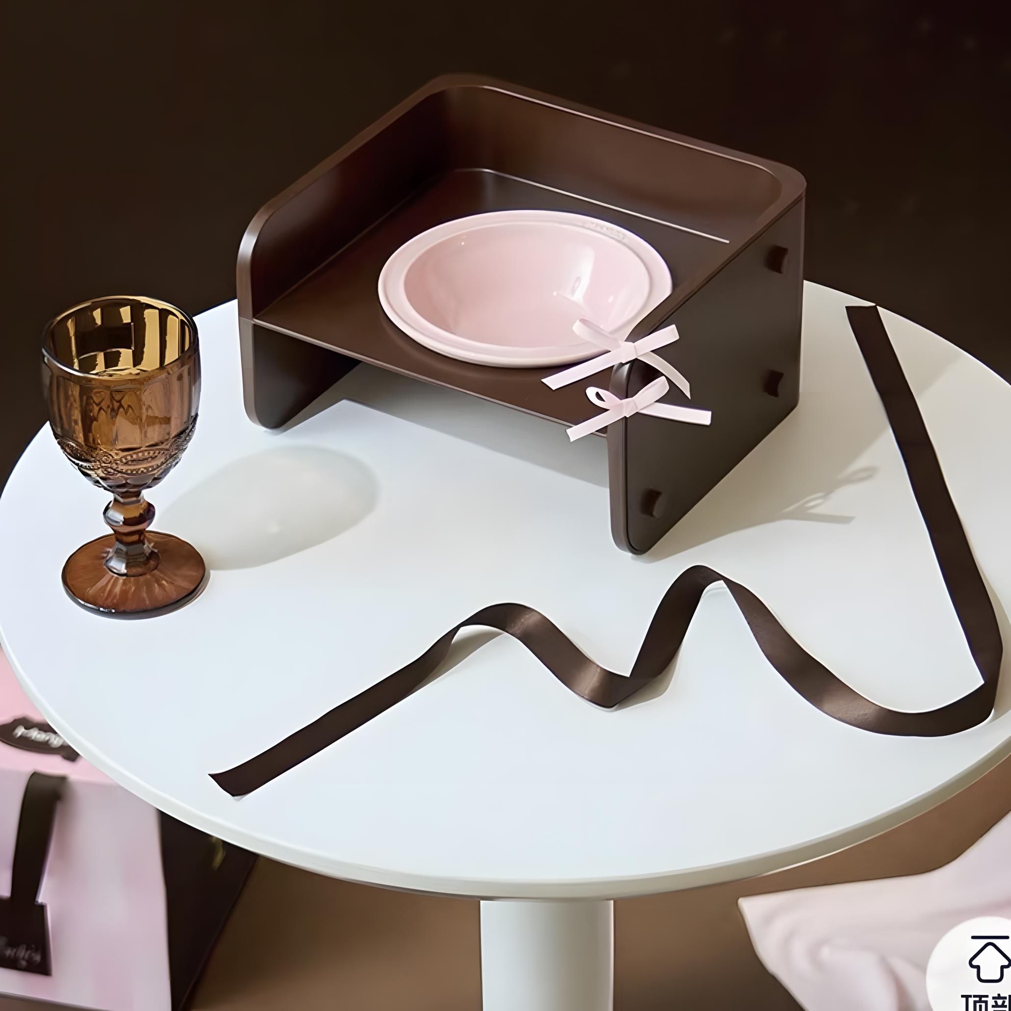 Close-up of the elevated cat bowl from the Mango Cannelés Patisserie Set, featuring a cocoa-brown stand and strawberry-pink ceramic dish styled on a white table
