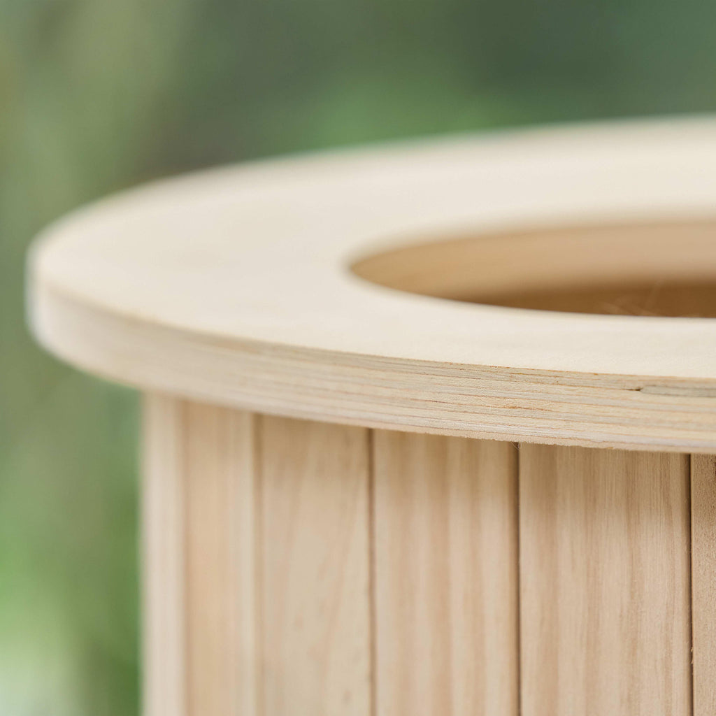 Close-up of the natural wood slat structure and curved rim of the cat house.