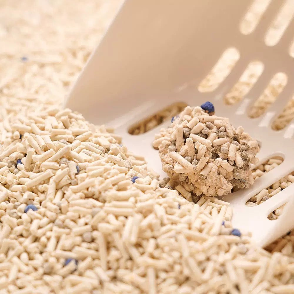 Close-up of a litter scoop lifting a solid clump. The bentonite blend locks liquid instantly, preventing sticky messes on the litter tray bottom