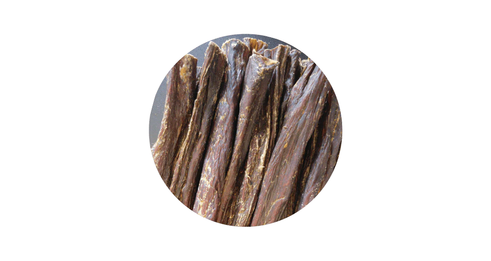 Close-up circular view of 100% pure air-dried beef jerky sticks for dogs, highlighting the natural, high-protein chewy texture perfect for training rewards.