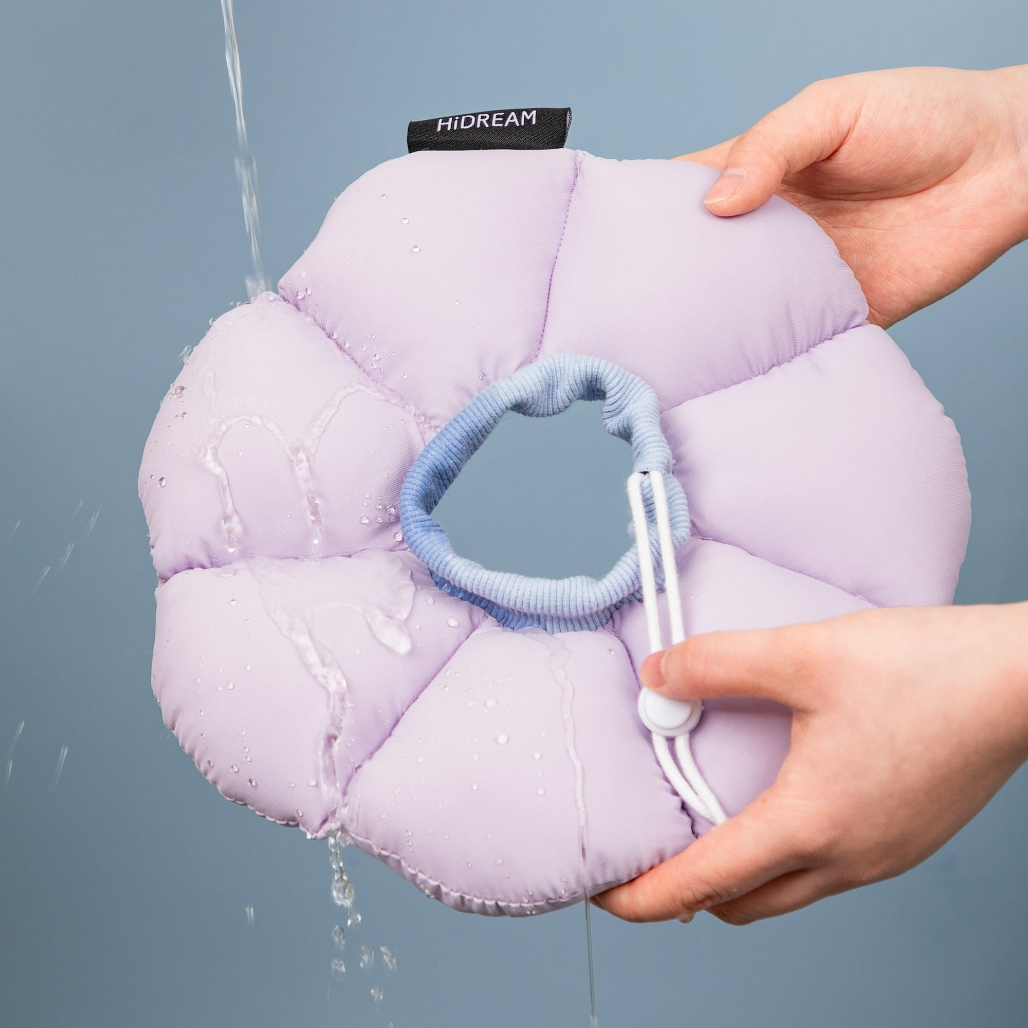 Water running over the purple HiDREAM soft recovery collar, demonstrating its water-resistant outer fabric that is easy to wash and maintain.