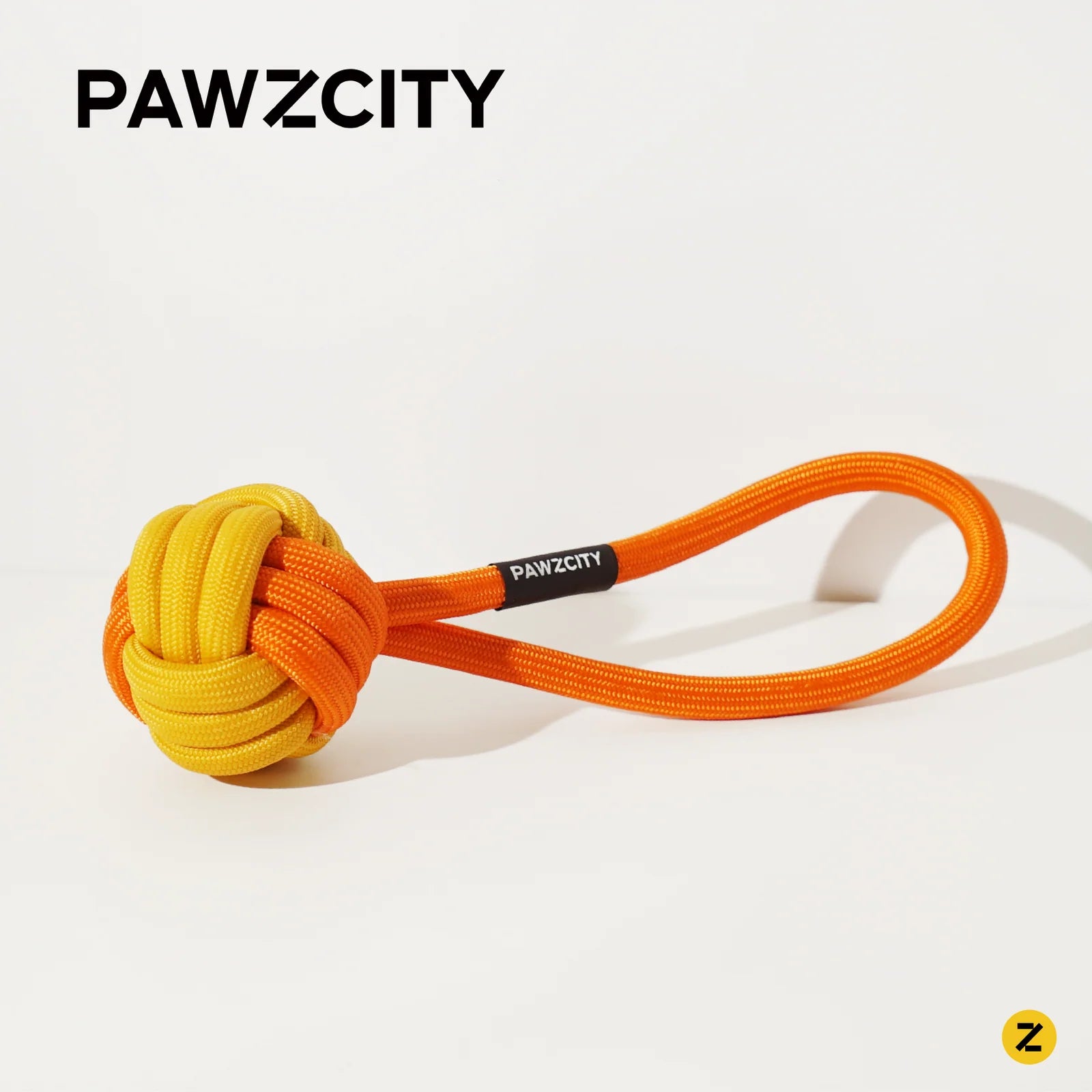 Orange and yellow dog toy with a loop on a white background, branded &