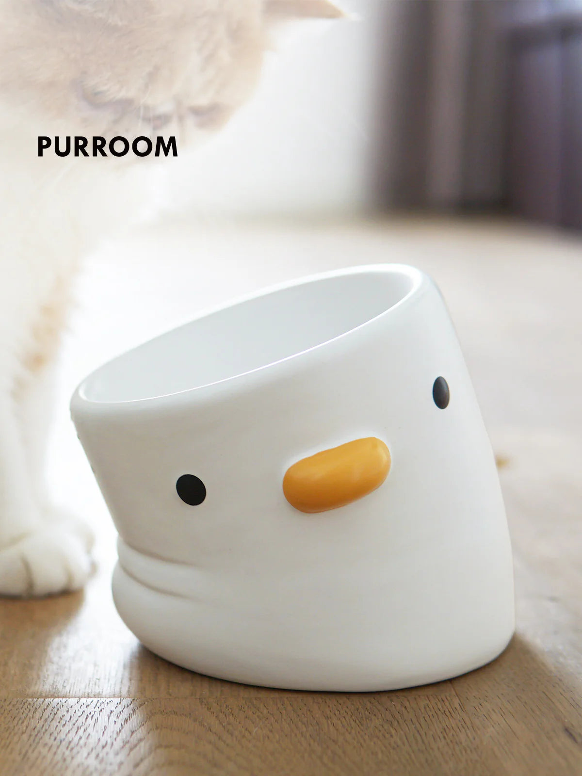 White ceramic chick-shaped bowl on a wooden surface with &