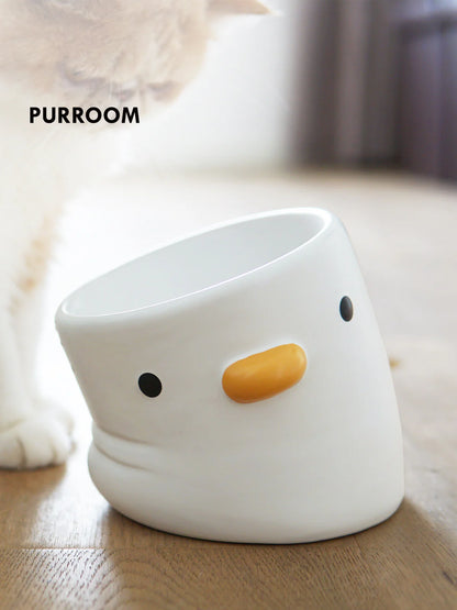 White ceramic chick-shaped bowl on a wooden surface with &