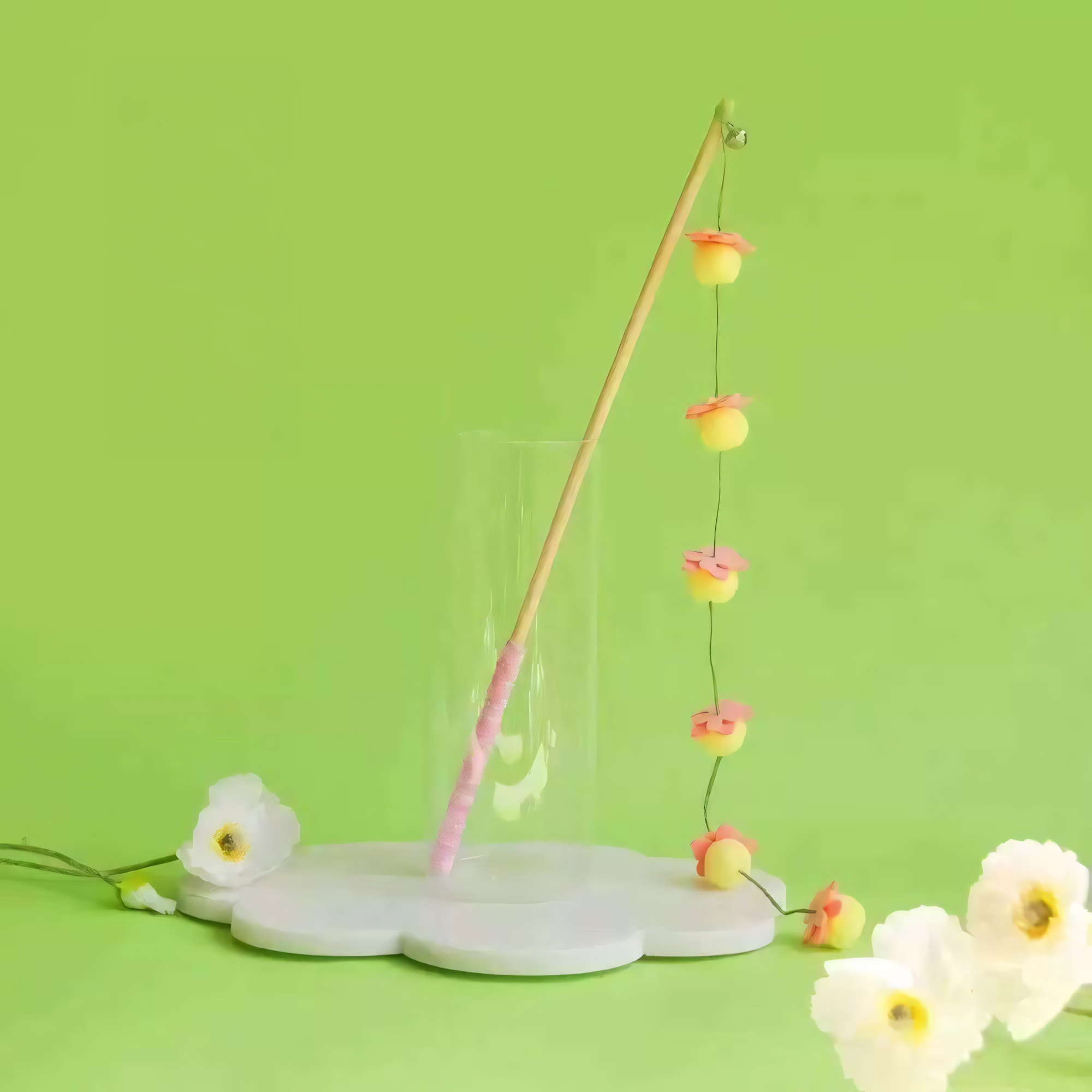 Peach Blossom style hand-crocheted wool cat teaser wand against a green background.