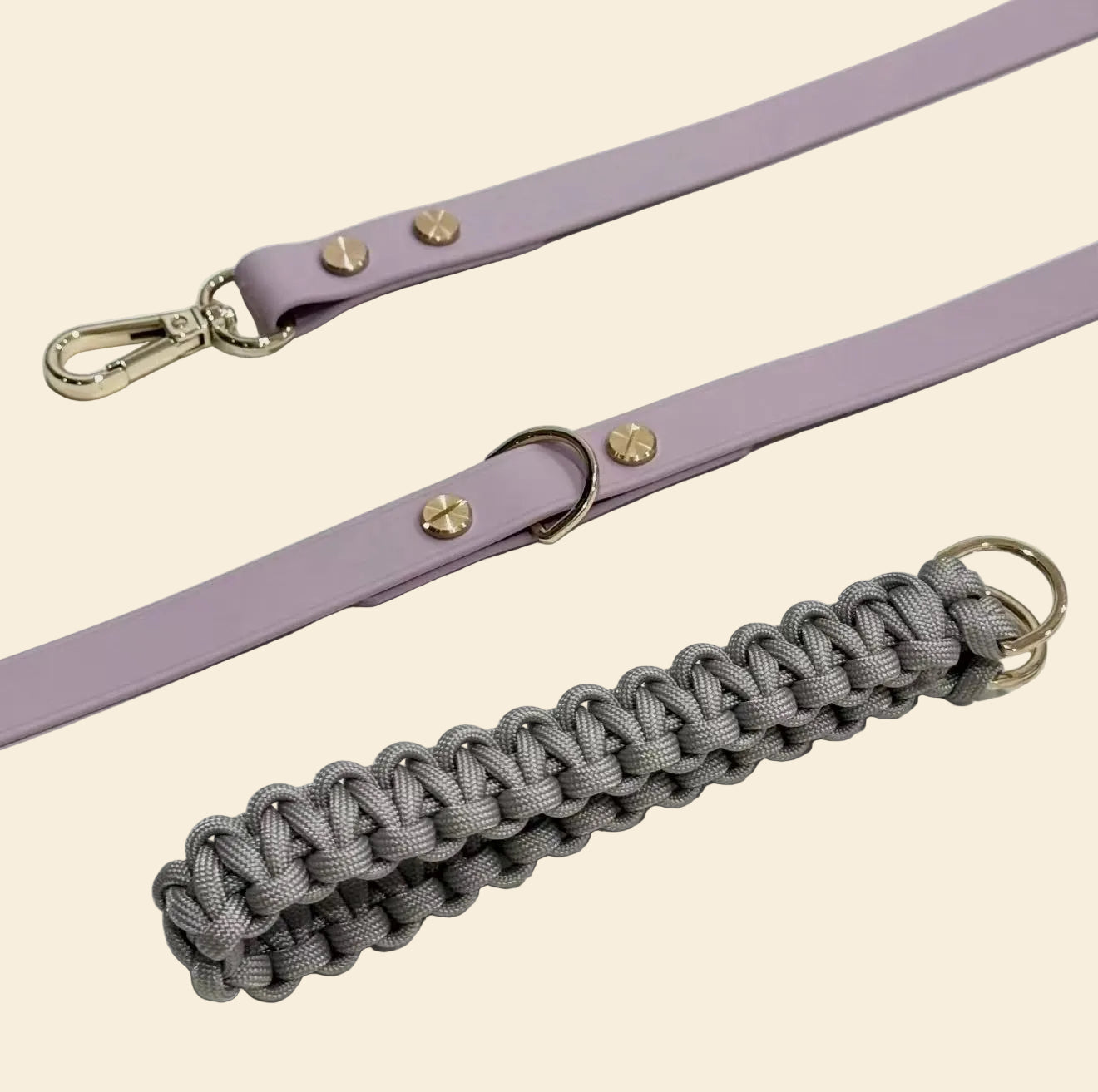 Purple leather strap with gold hardware and a gray braided handle on a white background