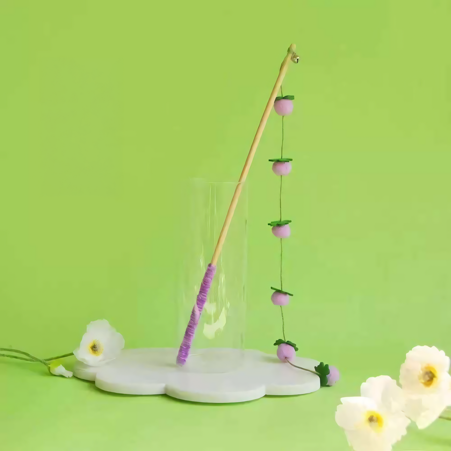 Purple Plum style hand-crocheted wool cat teaser wand against a green background.