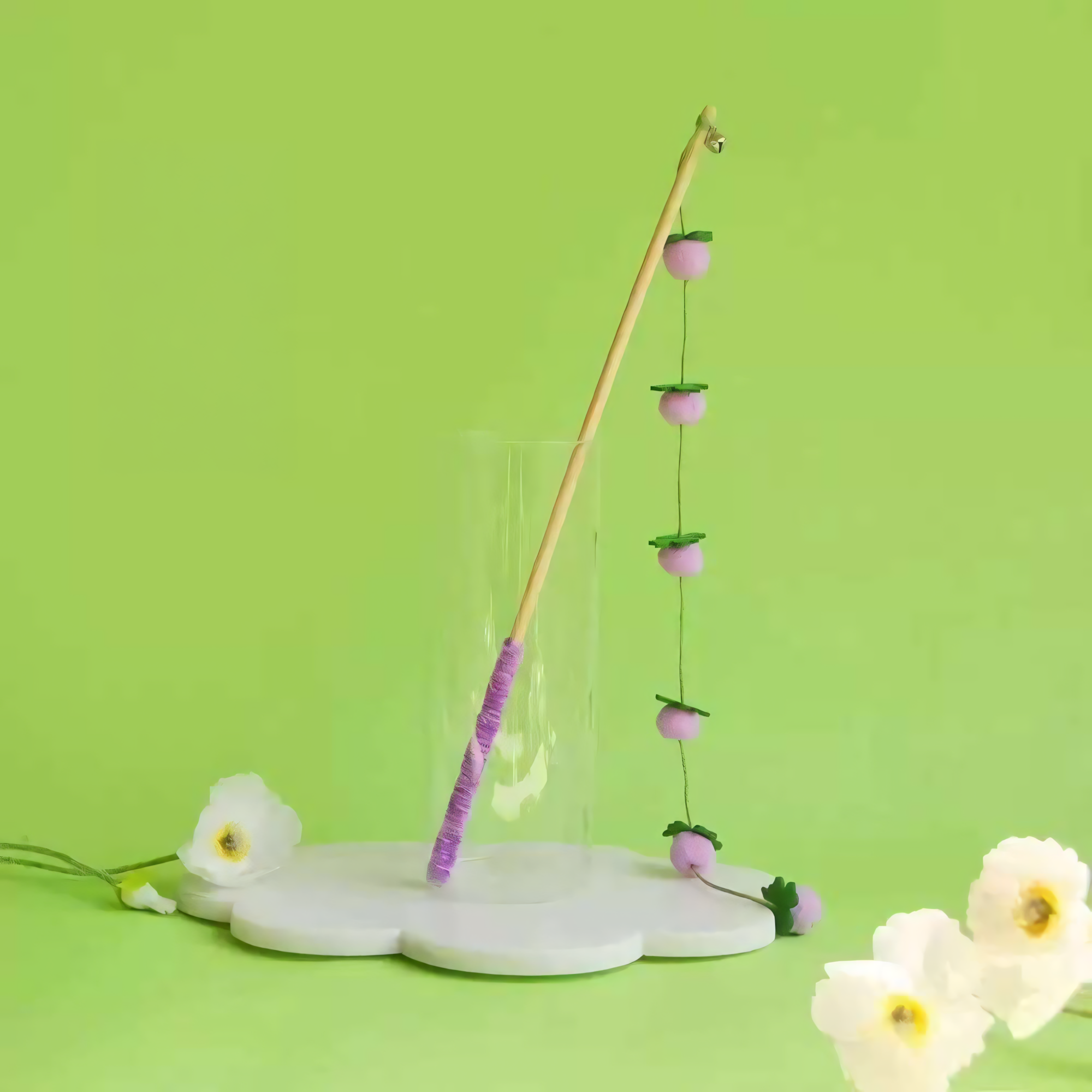 Purple Plum style hand-crocheted wool cat teaser wand against a green background.