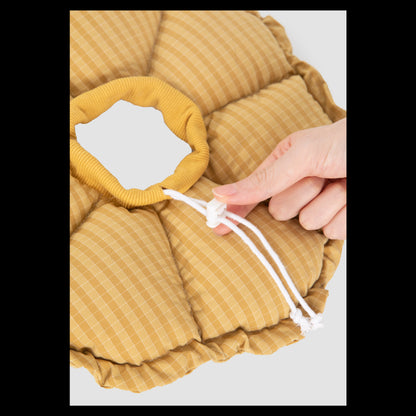 Close-up of a hand adjusting the toggle drawstring on the yellow gingham HiDREAM plush pet cone, showing the soft, ribbed inner neckband.