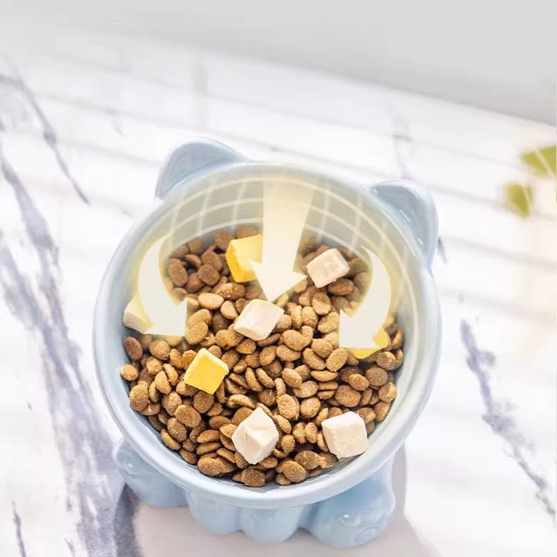 A top-down view of the blue elevated cat bowl filled with food, featuring curved downward arrows that illustrate how the smart interior design naturally gathers food to the center.