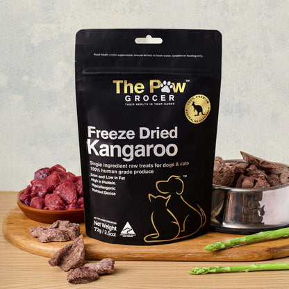 The Paw Grocer 72g Freeze-Dried Kangaroo pet treats displayed on a wooden board next to fresh raw meat and a silver bowl filled with the crunchy, hypoallergenic cubes.
