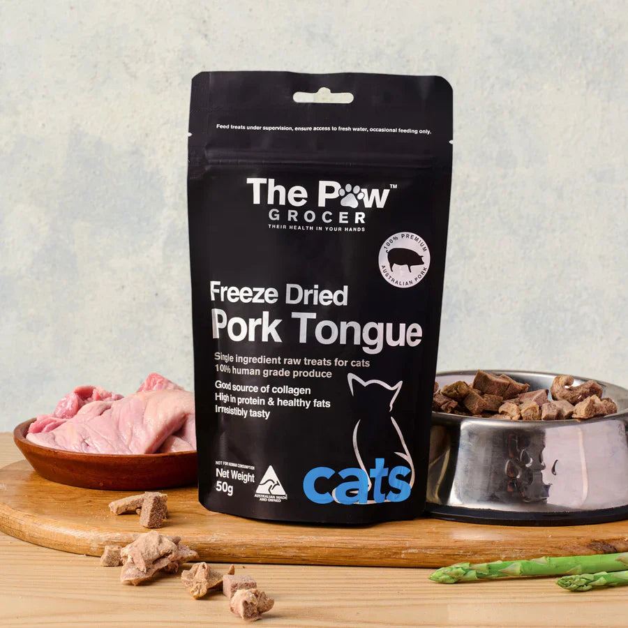 The Paw Grocer 50g Freeze-Dried Pork Tongue treats perfectly displayed on a wooden board next to fresh raw pork tongues and a silver bowl filled with the crunchy, rotational protein reward.
