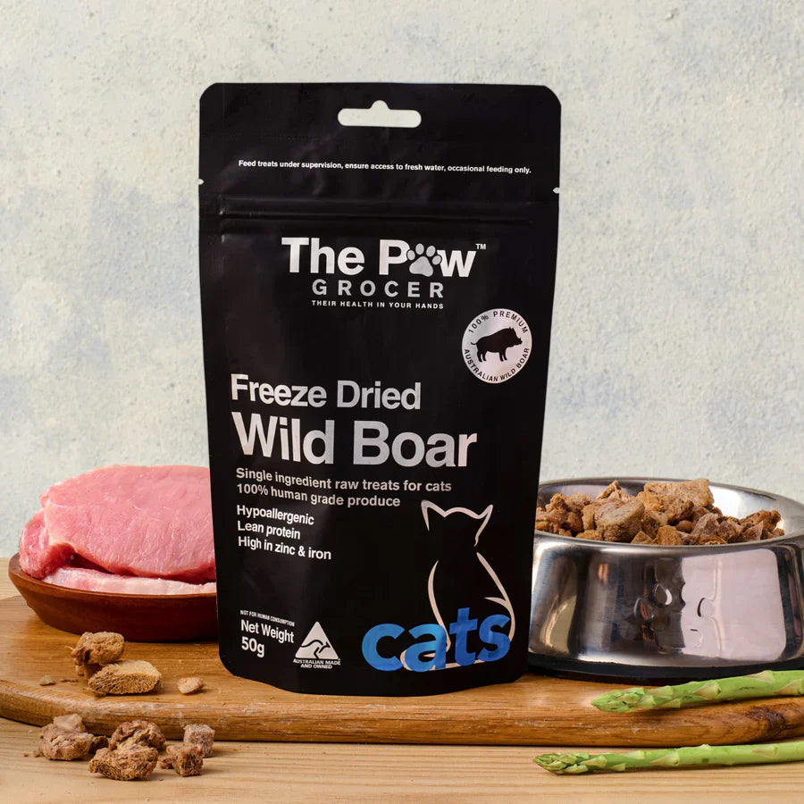 The Paw Grocer 50g Freeze-Dried Wild Boar cat treats displayed next to fresh raw meat and a silver bowl filled with the crunchy, hypoallergenic, single-ingredient cubes.