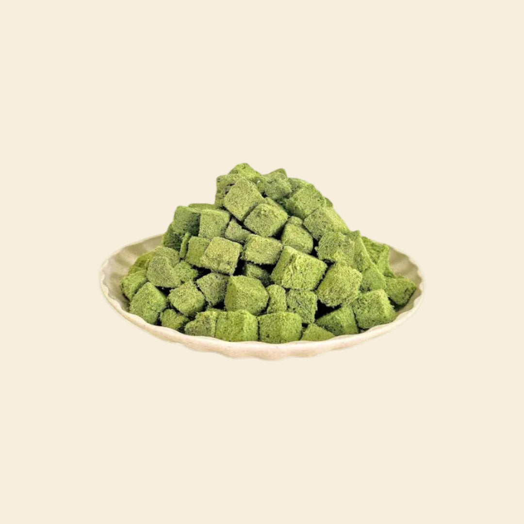 A  view of a small bowl overflowing with vibrant green, bite-sized freeze-dried cat grass chunks, highlighting the crunchy, high-protein texture perfect for training rewards or a meal topper.