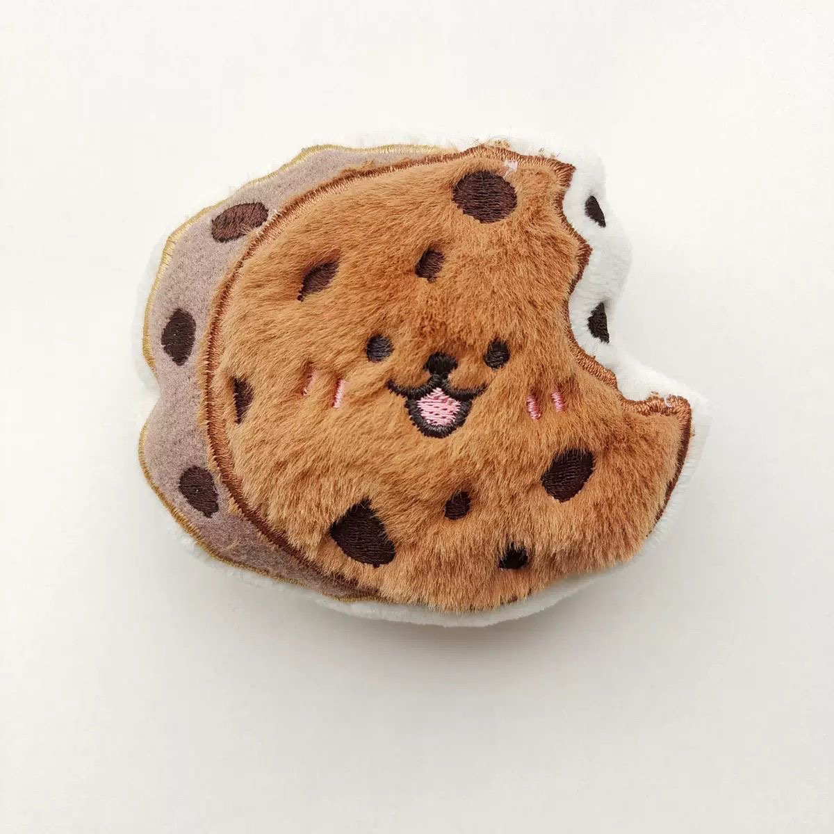 An 8cm "bitten" chocolate chip cookie plush toy with dark chocolate spots and a joyful embroidered expression.