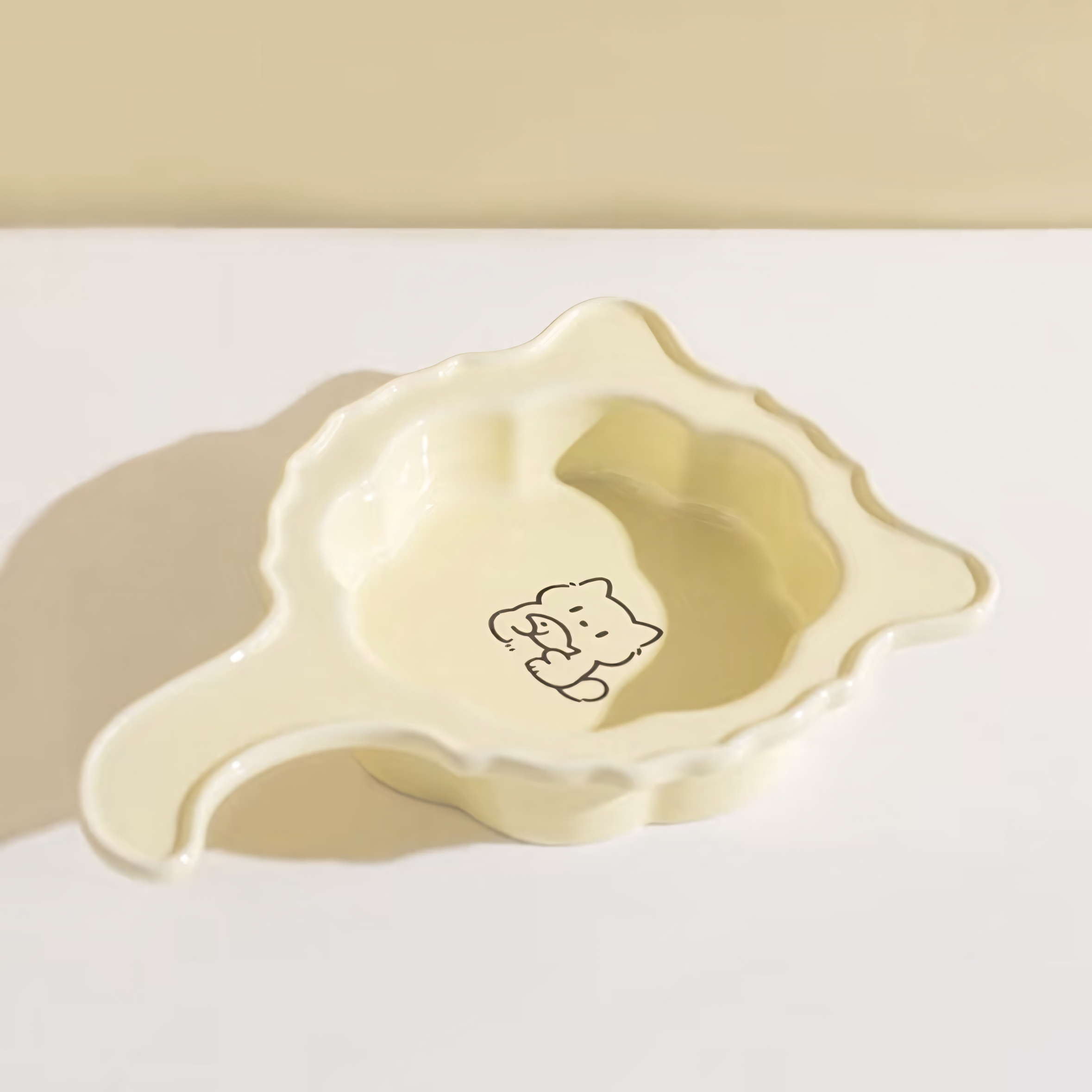 Top-down view of the Butter Yellow Crooked Tail pet plate, featuring a cute minimalist cat illustration in the center of the scalloped floral dish.
