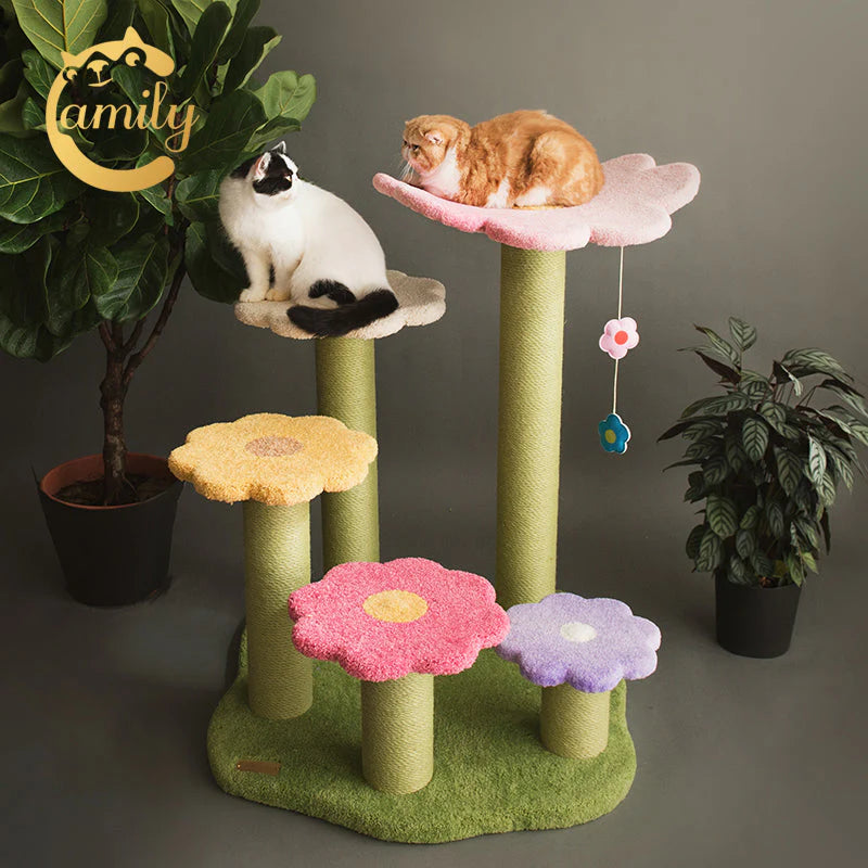 Two cats enjoying the Camily Flower Ladder Cat Tree in a cozy room decorated with plants. An orange cat rests on the top pink flower platform, while a black and white cat sits on a lower step, showcasing the accessible multi-level design.