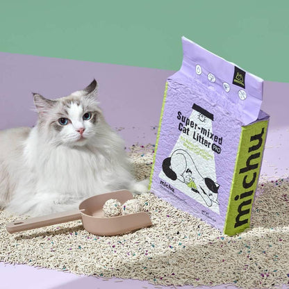A Ragdoll cat lying next to an open bag of Michu mixed tofu cat litter and a scoop holding two solid, mess-free clumps, demonstrating the comfortable, sand-like digging surface.