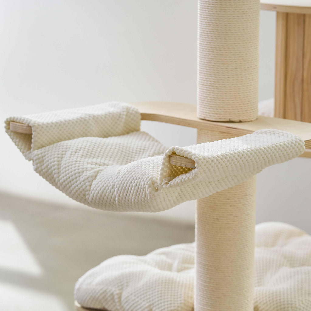 Close-up view of a soft, padded fabric hammock attached to the wooden cat tree pillar.
