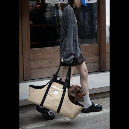 Lifestyle shot of a person walking outdoors with the Clay Brown Sausage Dog Carrier Tote, demonstrating its style and portability for travel.