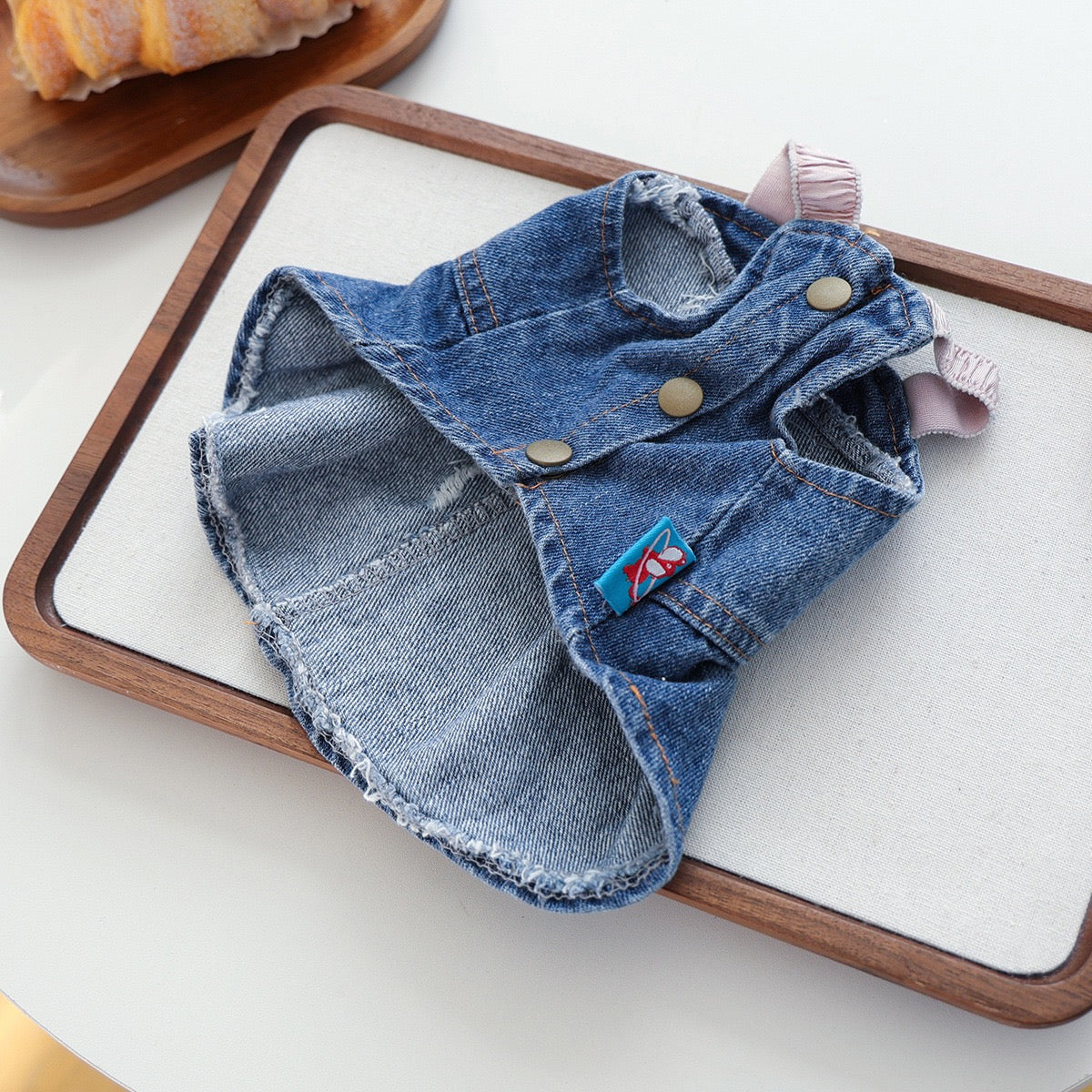 Front flat lay of the denim dog dress showing the bronze snap buttons and the tailored belly cut-out designed specifically for easy bathroom breaks.