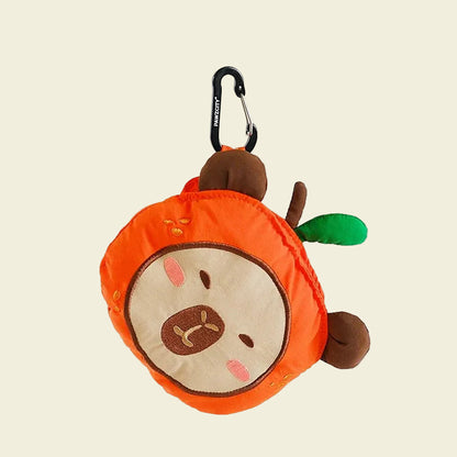 Front view of the soft plush PAWZCITY Capybara dog poop bag holder suspended by its clip, highlighting the relaxed capybara face, brown ears, and green leaf detail.