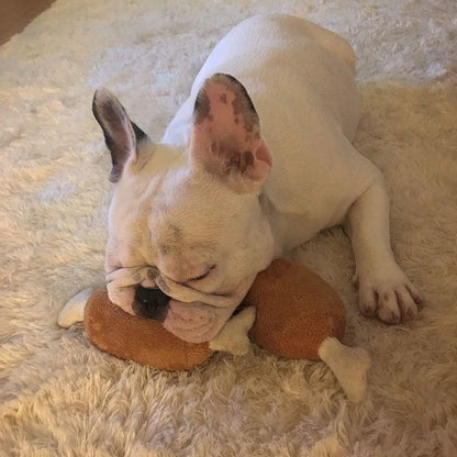 A sleepy French Bulldog using two plush chicken leg toys as a comfortable pillow on a soft rug, demonstrating its use as a cuddle buddy.