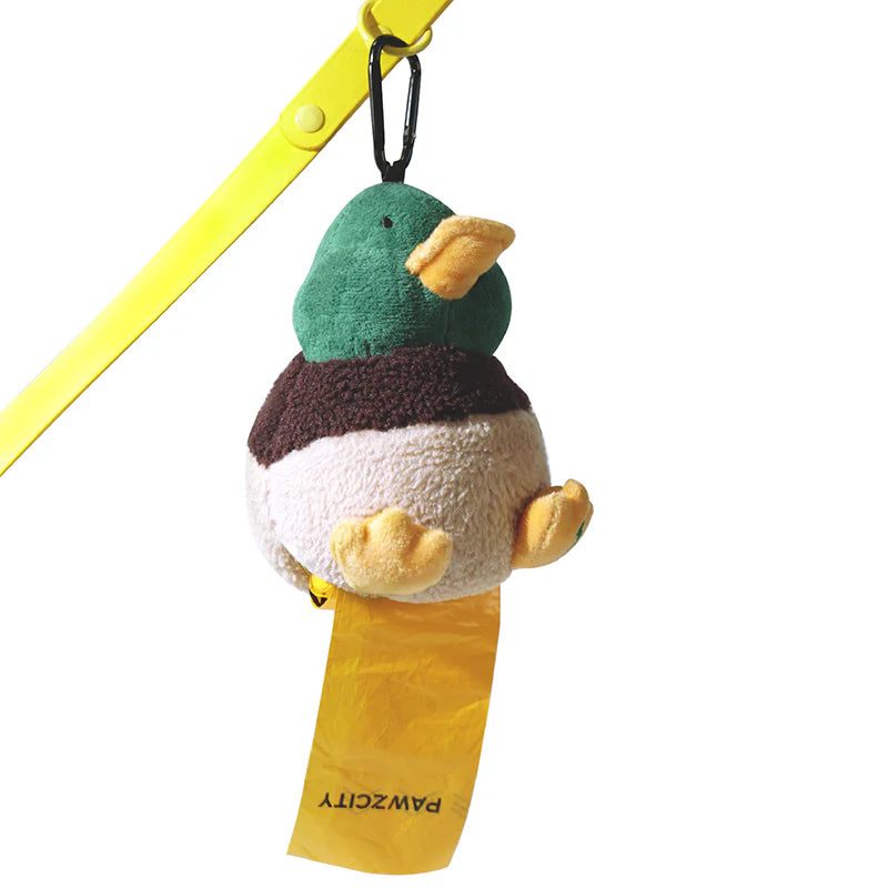 The PAWZCITY duck waste bag dispenser clipped to a yellow dog leash, actively dispensing a matching yellow PAWZCITY poop bag from the bottom.