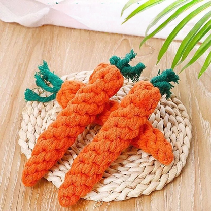 Three tightly braided cotton rope carrot toys arranged on a woven seagrass mat, highlighting the natural fibers and the bright orange and green colors.