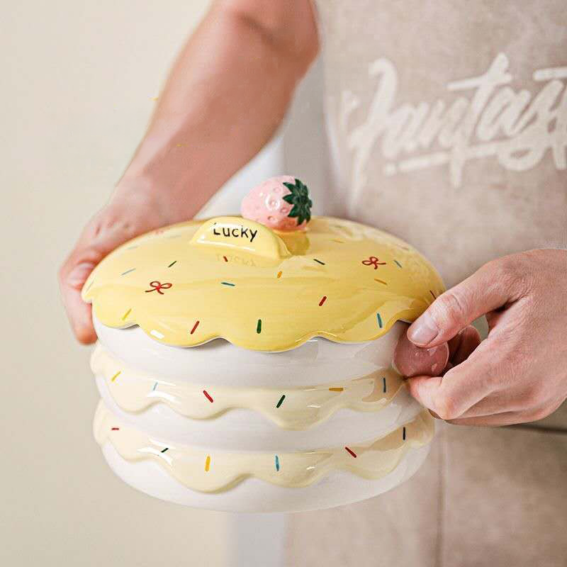 A person securely holding the large strawberry cake ceramic pet bowl by its convenient pink side handles, demonstrating how easy it is to lift and carry the food dish.