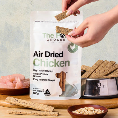 A hand breaking The Paw Grocer air-dried chicken straps into smaller bite-sized pieces. Perfect for repetitive dog training sessions without messy crumbs.