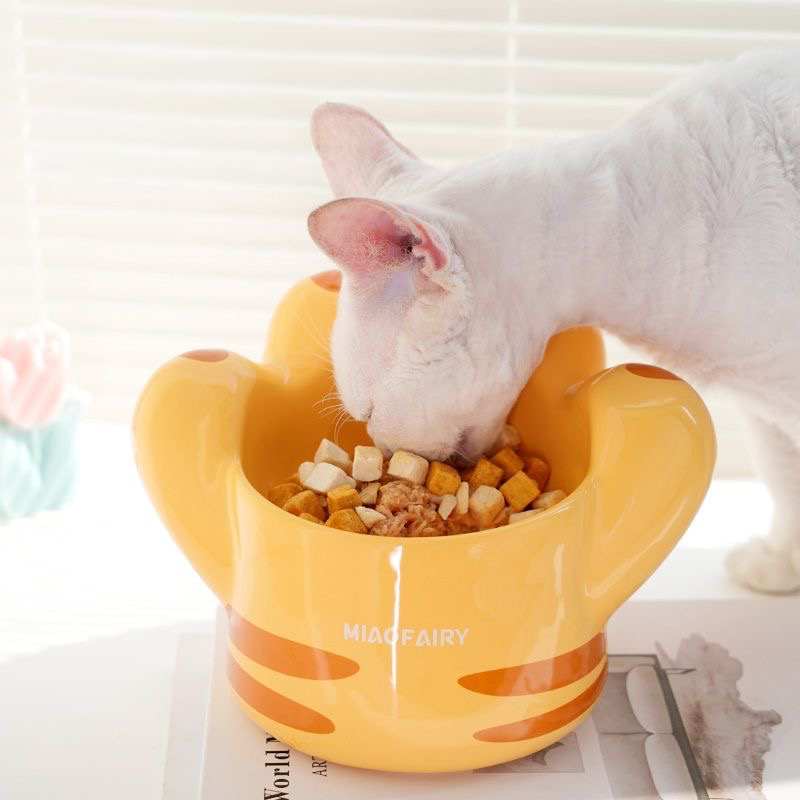 A white cat eating from the orange Giant Cat Paw ceramic bowl. The side view demonstrates how the 13cm elevated base promotes a healthy dining posture, reducing neck strain and stomach pressure.